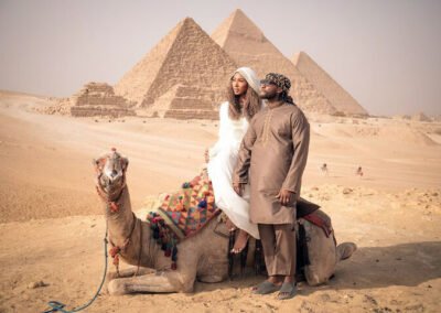 Couples taking photo on camel in front of pyramids