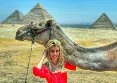 A lady beside a camel in front of Giza Pyramids